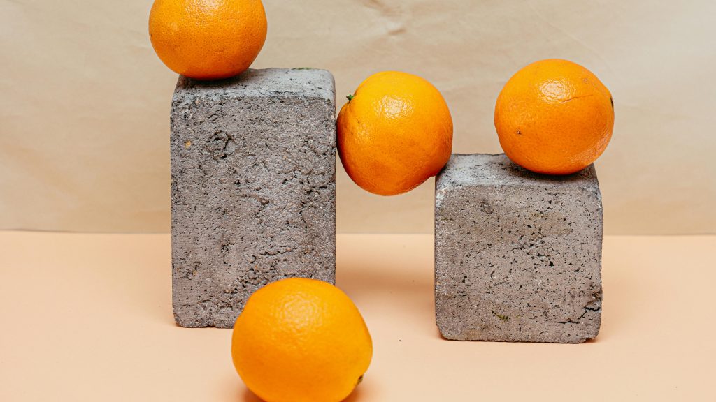 twee stenen blokken en daarop en tussen 4 sinaasappels
