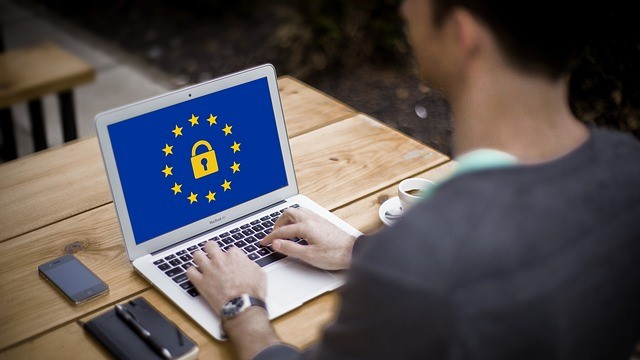 Man achter laptop met daarop europese unie scherm met in het midden een cyber-slotje