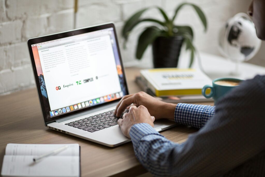 Man achter laptop, van achterzijde gefotografeerd, handen op toetsenbord