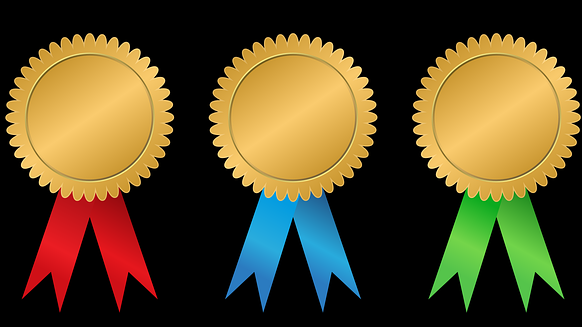 3 medailles (microcredentials) in goud met rode, blauwe en groene lintjes op een rij