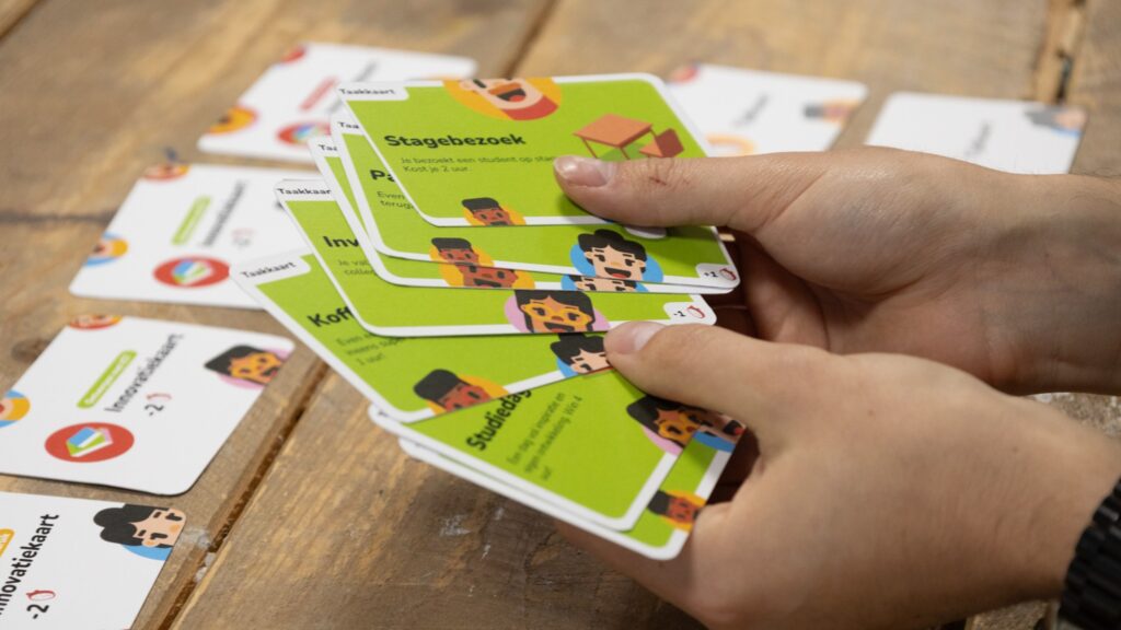 Foto met twee handen die de groene spelkaarten van het spel Digidoen vasthouden.