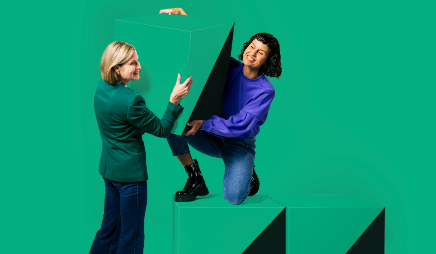 oto van twee dames die een blok optillen tegen een groen decor
