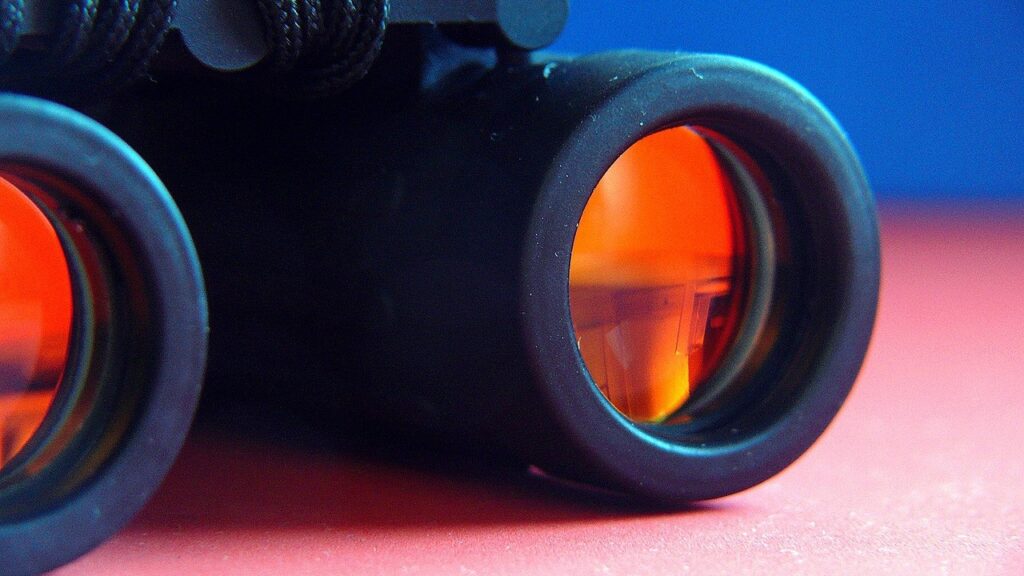 verrekijker, ingezoomd op glas, oranjegloed en achtergrond blauw roze