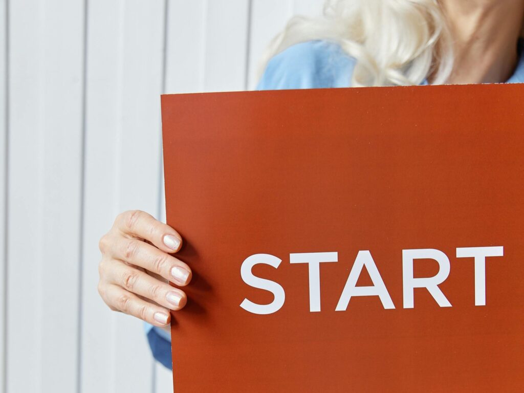 Foto met hand op rood bord met daarop het woord Start