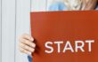 Foto met hand op rood bord met daarop het woord Start