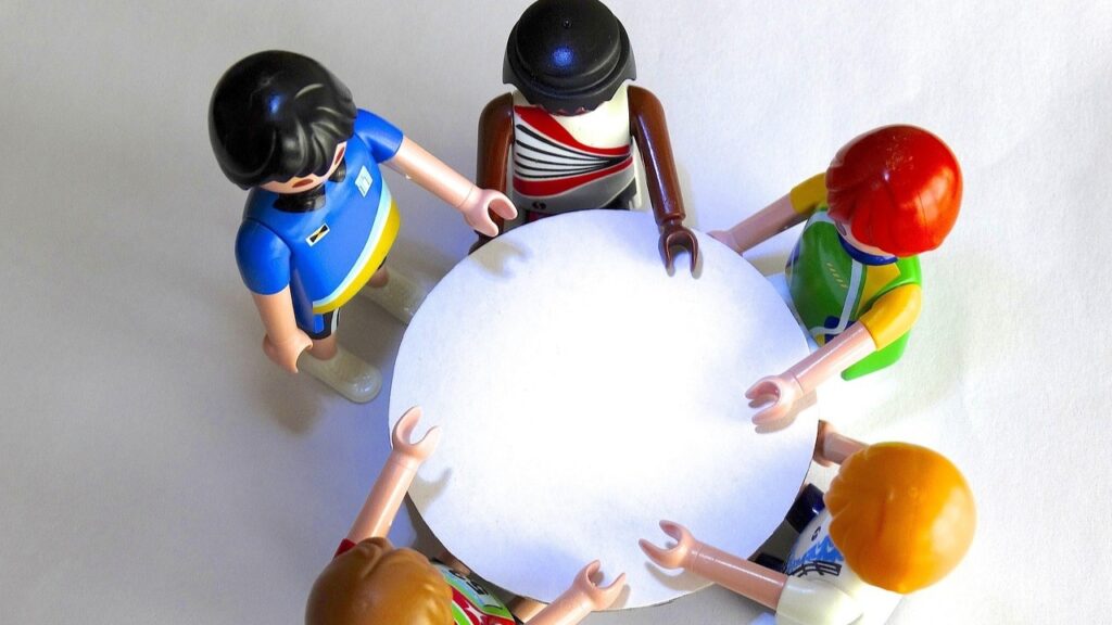 5 Playmobil poppetjes aan een ronde tafel, van bovenaf gefotografeerd