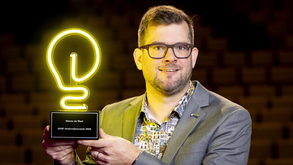 foto Menno de Waal met award in de hand, een geel lampje