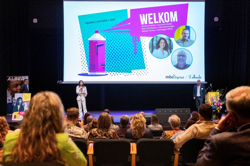 foto van podium conferentie in de Doelen, met sprekers en mensen in de zaal, van achter gefotografeerd.