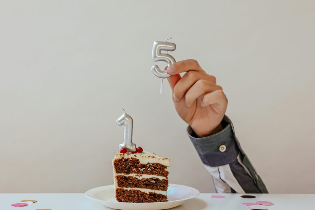 foto van hand die nummer vijf kaarsje op een taart doet waar al een 1 op staat